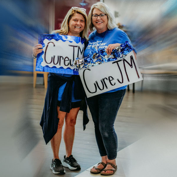 Alyssa Carpenter and friend with Cure JM signs