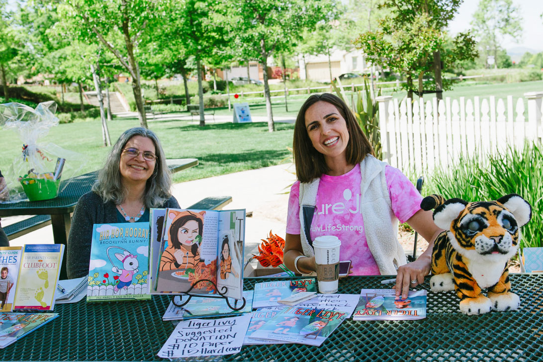 Smiling volunteers at a table with fundraising items