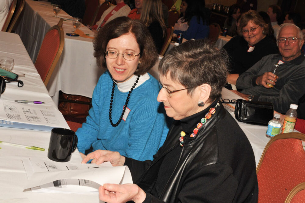 Two women reading notes at a conference.