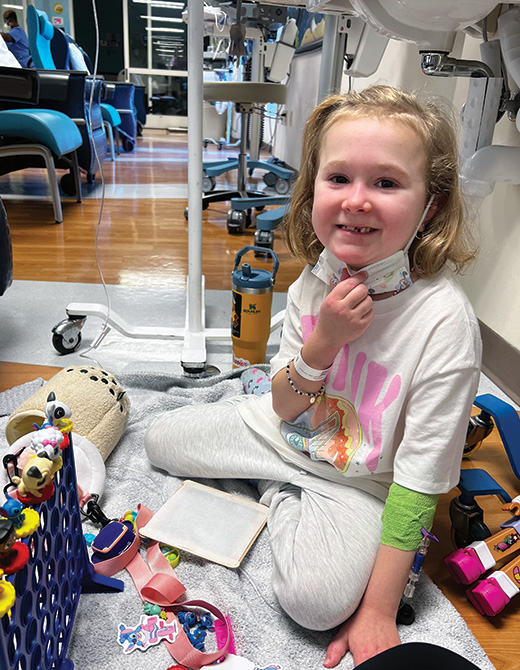 Young girl with juvenile dermatomyositis playing in IV treatment room