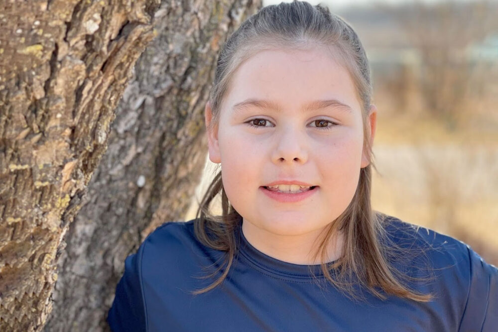 Niña apoyada en un árbol