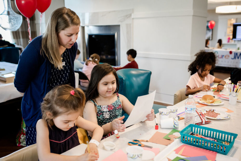 A teacher with children doing crafts.