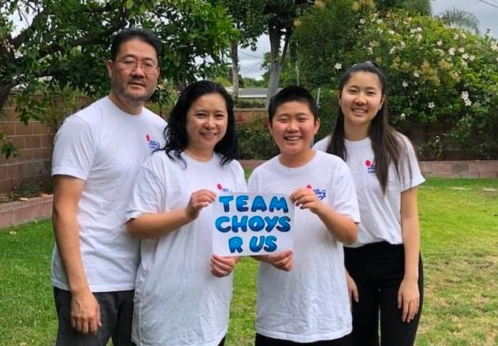 Smiling family holding "Team Choys R Us" sign